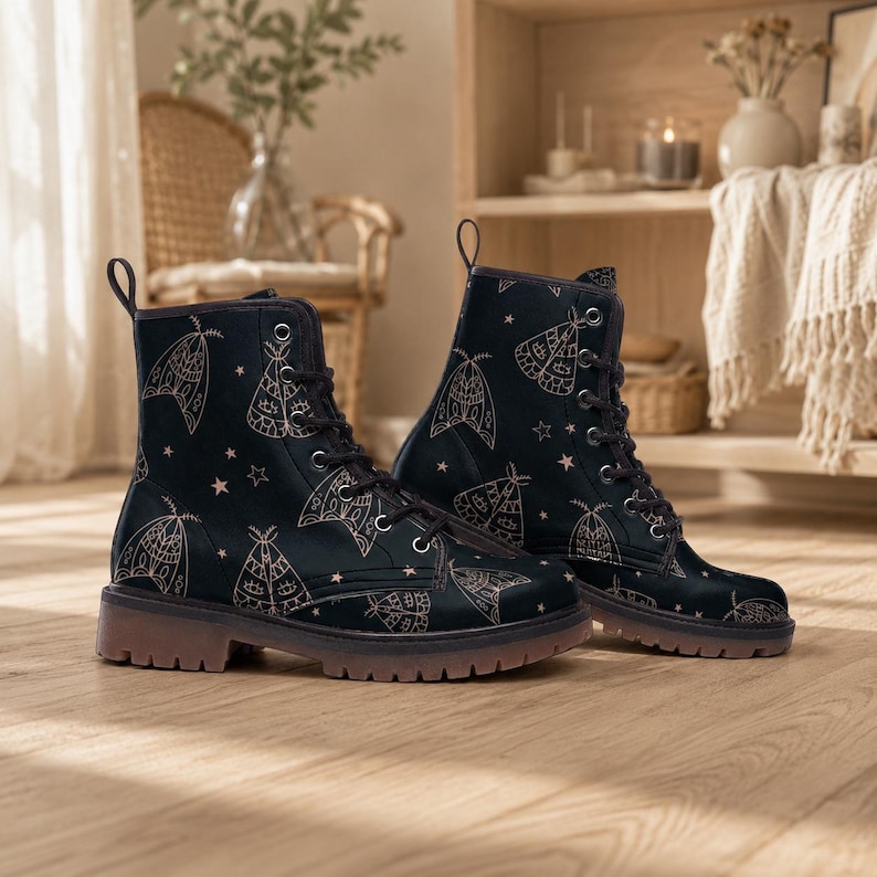May include: A pair of black lace-up boots featuring a repeating pattern of light-colored moth illustrations and small stars. The boots have black laces, silver-toned metal eyelets, and a thick, translucent brown lug sole for traction and durability.