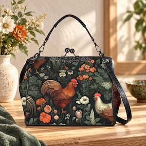 May include: A structured handbag featuring a dark background with a pattern of roosters, hens, and orange and white flowers. The bag has a black frame, a top handle, a kiss-lock clasp, and a detachable shoulder strap with black hardware.