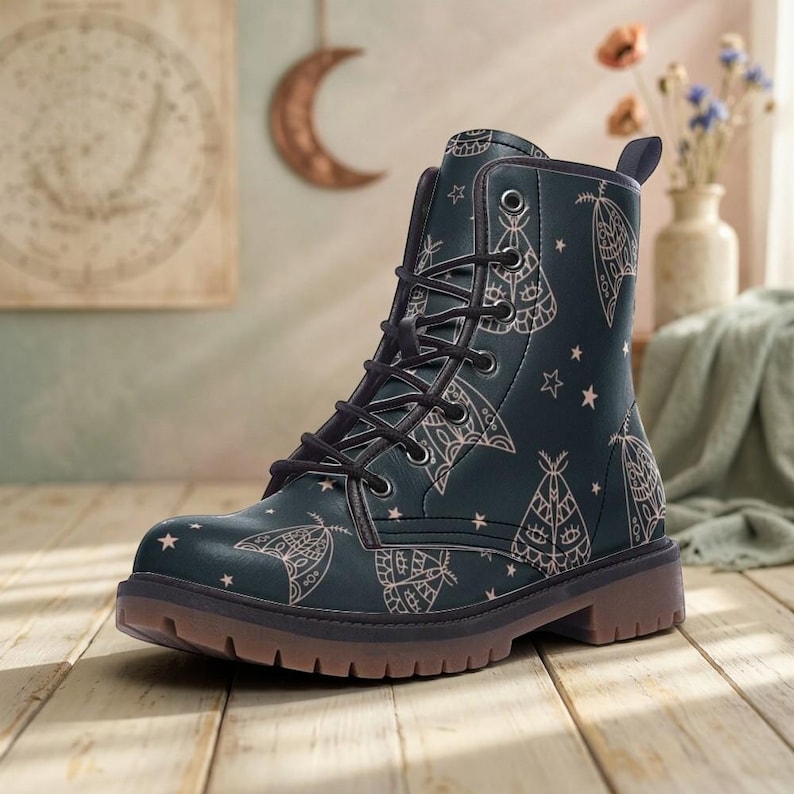 May include: A dark teal lace-up ankle boot featuring a repeating pattern of light-colored moths and small stars. The boot has a rounded toe, black laces, metal eyelets, a pull tab at the heel, and a thick, textured brown rubber sole.