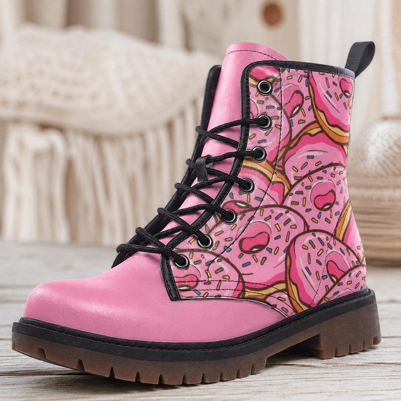 Op de afbeelding: Een roze enkelboot met een herhalend patroon van roze geglazuurde donuts met kleurrijke hagelslag. De boot heeft zwarte veters, zwarte metalen oogjes, een zwart treklipje bij de hiel en een dikke, donkerbruine profielzool voor extra grip.