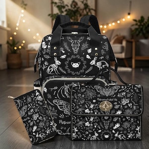 A matching set including the black backpack, a handbag, and a zippered wallet arranged on a floor.