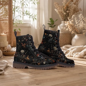 May include: A pair of black combat boots with a floral pattern in shades of orange, yellow, and white. The boots have a lace-up design and a dark brown sole. The boots are made of a soft, comfortable material.