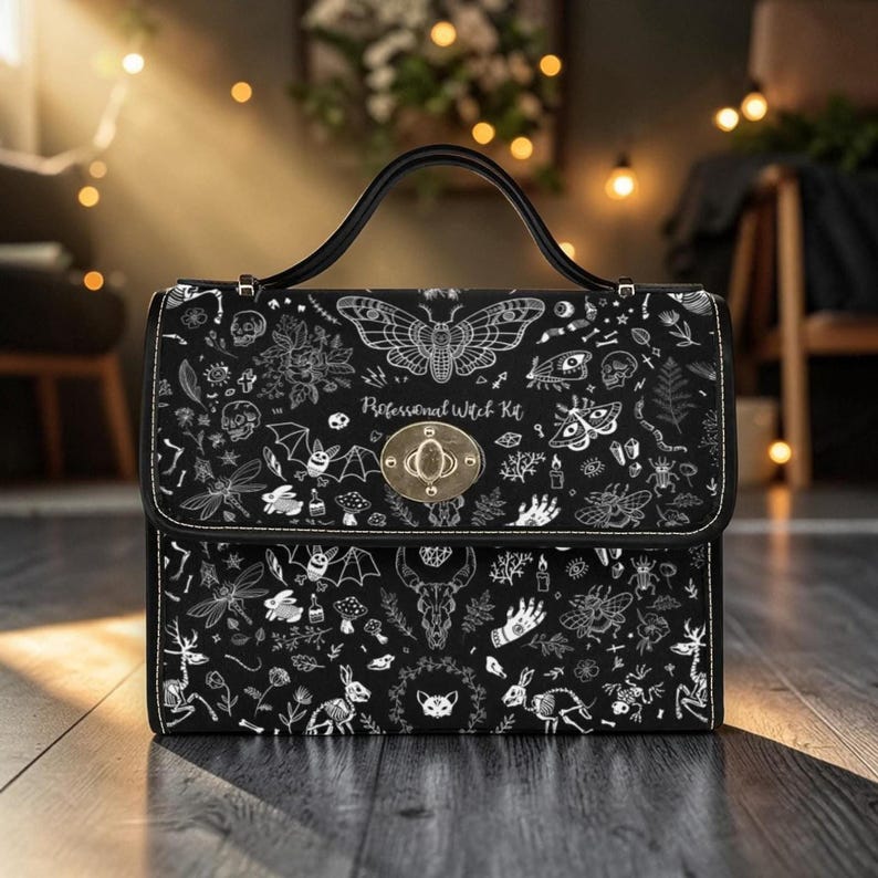 A structured black handbag with a top handle and a gold twist-lock closure, featuring a white moth pattern.