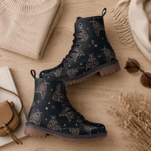 May include: A pair of black lace-up boots featuring a repeating pattern of light-colored moths and small stars. The boots have black laces, metal eyelets, and a thick, translucent brown rubber sole with a visible tread pattern on the bottom edge.