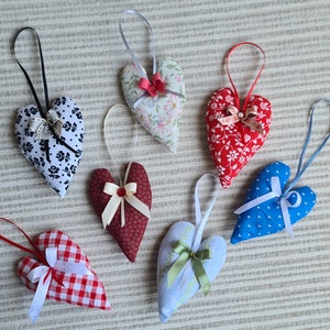 May include: Seven handmade heart-shaped fabric sachets with different patterns and colours. Each sachet has a ribbon tied around it.