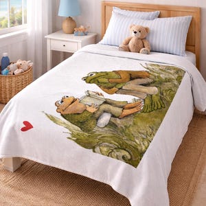 May include: White bedspread featuring a whimsical illustration of two frogs reading a book. The artwork is in shades of green, brown, and tan. A small red heart is visible on the bedspread. The bed is in a child's bedroom.