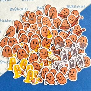 Puede incluir: Una colección de pegatinas con forma de patata, cada una con una cara sonriente y tocando un instrumento musical. Los instrumentos incluyen trompetas, trombones y tubas. Las pegatinas son marrones con detalles blancos y amarillos.