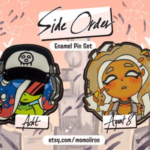 Puede incluir: Juego de pines de esmalte con dos personajes de dibujos animados de "Side Order". Un personaje lleva un sombrero negro con una calavera, el otro tiene el pelo castaño. Se muestra el texto "Side Order" y "Enamel Pin Set".