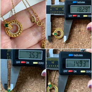 May include: A gold necklace with a pendant featuring a green stone and a circular design. The pendant measures 1.53 inches in diameter and the necklace is 18.29 inches long.