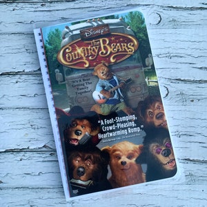 May include: A VHS tape for the Disney movie "The Country Bears." The cover features a group of bears playing music and the text "It's a Bear Getting the Family Together!" and "A Foot-Stomping, Crowd-Pleasing, Heartwarming Romp."