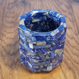 May include: A blue and white lapis lazuli stone pencil holder with a hexagonal shape.