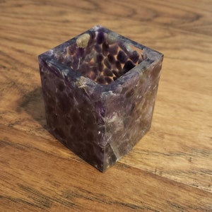 May include: A square-shaped amethyst crystal container with a rough, textured surface. The container is made of many small amethyst crystals that have been fused together.
