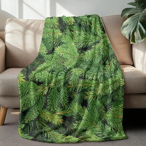 Könnte beinhalten: Eine grüne und braune Kuscheldecke mit einem Muster aus Kiefernästen. Die Decke ist aus weichem, plüschem Stoff und perfekt zum Kuscheln auf der Couch.