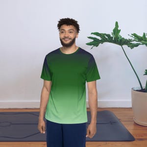 May include: A short-sleeved t-shirt with a gradient design, transitioning from a dark navy blue at the top to a light green at the bottom. The shirt is worn with navy blue shorts. The overall style is casual and sporty.