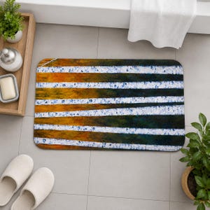 Op de afbeelding: Rechthoekige badmat met horizontale strepen in tinten goud, groen en blauw, afgewisseld met witte strepen. De mat heeft afgeronde hoeken en een textuur, geschikt voor een badkamer.