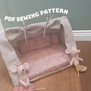 Könnte beinhalten: PDF-Nähmuster für ein Puppenhaus-Sofa mit einem Baldachin aus Leinen. Das Sofa ist rosa und weiß mit einer gesteppten Rückenlehne und einer rosa-weiß gestreiften Matratze. Zwei kleine Mäusepuppen sitzen in der Nähe des Sofas.