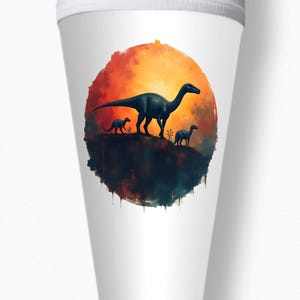 Puede incluir: Un cono de papel blanco con una ilustración de acuarela de tres dinosaurios en silueta contra una puesta de sol. Los dinosaurios caminan en línea, con el dinosaurio más grande al frente.
