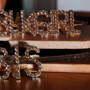 May include: Two gold hair clips with rhinestones spelling out "BIKERGIRL" and "SIS".