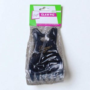 May include: A black claw hair clip in a clear plastic package. The packaging has a green and white label with the text "CLAW PIC" and the brand name "Diane". The clip is a hair accessory.