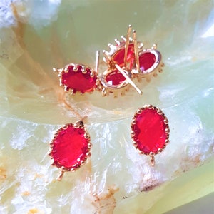 Può includere: Un set di quattro orecchini dorati con accenti di pietre preziose rosse. Gli orecchini hanno un design semplice con una piccola pietra preziosa rotonda al centro.