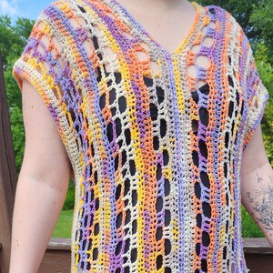 May include: A crocheted, multi-colored, sleeveless top with a V-neck and a loose, open-weave design. The top is made with a variety of colors, including purple, orange, yellow, and white.