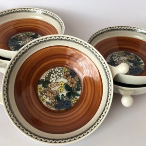 Può includere: Set di quattro ciotole in ceramica bianca con strisce marroni e arancioni e disegni floreali. Ogni ciotola ha due manici e un bordo rialzato.