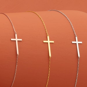 May include: Three delicate necklaces with a simple cross pendant. The necklaces are silver, gold, and rose gold.