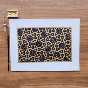 Peut inclure: Œuvre d'art à motif géométrique avec un design or et bleu marine. L'œuvre présente un motif en forme d'étoile répétitif avec un fond bleu foncé et des lignes dorées. Un petit récipient de peinture dorée, une plume en verre et un pinceau sont visibles.