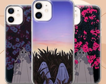 May include: Three clear phone cases featuring illustrations of ghosts. The left case shows a ghost with blue flowers, the center case depicts two ghosts in a cornfield at sunset, and the right case displays a ghost with vibrant pink flowers.
