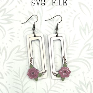 May include: White rectangular earrings with a floral design. The earrings have a dark metal hook and a decorative flower with green leaves. The text "Glowforge Ready" and "SVG FILE" are at the top. The text "not a physical product" is at the bottom.