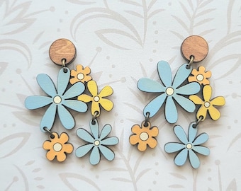 Könnte beinhalten: Ein Paar blaue und gelbe Blumenohrringe mit einem Holzaufsatz. Die Ohrringe sind so konzipiert, dass sie auf einer Glowforge ausgeschnitten werden können. "Glowforge Ready SVG FILE" steht oben im Bild. "not a physical product" steht unten im Bild.
