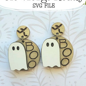 May include: A pair of wooden earrings featuring a white ghost and the word "BOO" in gold. The earrings are designed for a Glowforge and are not a physical product.
