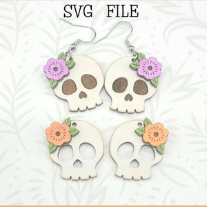 May include: A digital file for a pair of wooden skull earrings with floral accents. The earrings are available in two color variations: pink and orange flowers. The file is ready to be used with a Glowforge.