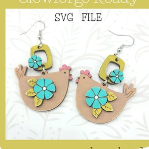 May include: A pair of laser cut wooden earrings featuring a brown chicken with a yellow flower and green leaves, a turquoise flower, and a yellow square. The earrings are attached to silver hooks. "Glowforge Ready SVG FILE" and "not a physical product" are written below the earrings.