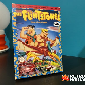 Könnte beinhalten: Eine Vintage-Videospielkassette für das Nintendo Entertainment System mit den Feuerstein-Familie. Die Schachtel zeigt Fred und Barney, die auf einem Pterodactylus reiten. Der Text auf der Schachtel lautet "The Flintstones" und "Sorpresa al Pico del Dinosauro".