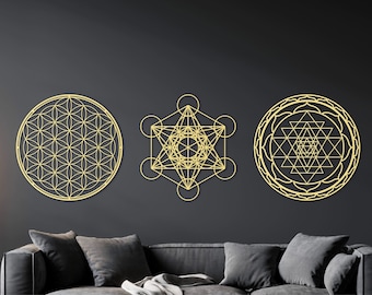 May include: Three gold metal wall decor pieces featuring geometric designs. The designs are a flower of life, a metatron's cube, and a sri yantra.