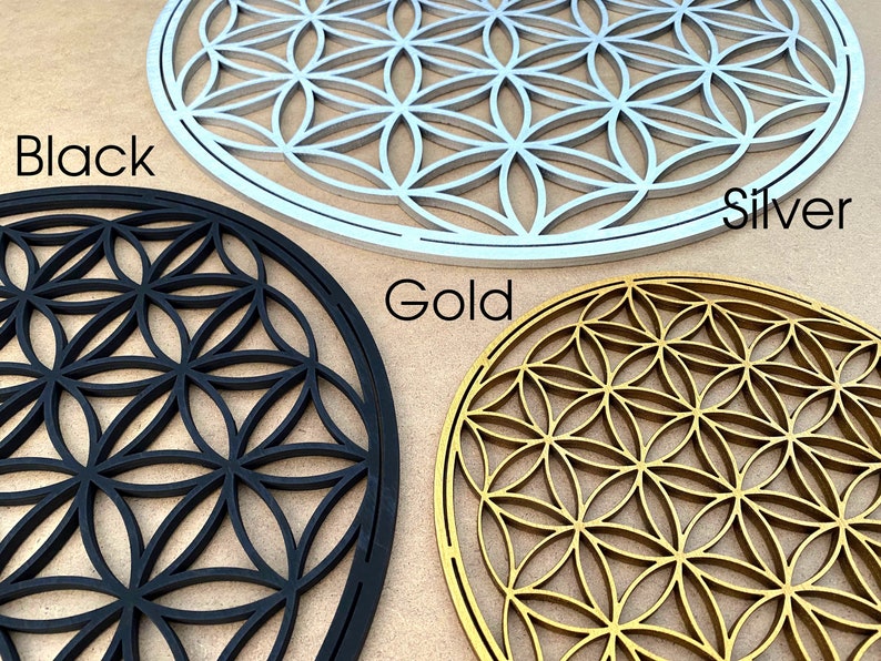 May include: Three wooden wall decor pieces in the shape of a flower of life pattern. The pieces are in black, silver, and gold.
