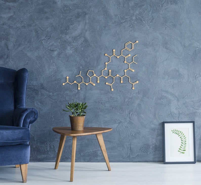 K&ouml;nnte beinhalten: Ein blauer Sessel steht neben einem Holz-Beistelltisch mit einer Topfpflanze. Ein geometrisches Wanddekor aus Holz h&auml;ngt an einer blauen, strukturierten Wand hinter dem Tisch. Ein gerahmter Druck mit einem gr&uuml;nen Blattdesign h&auml;ngt an der Wand rechts neben dem Tisch.