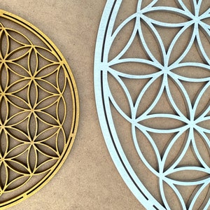 May include: Two wooden wall decor pieces in the shape of a flower of life. One is gold and the other is silver.