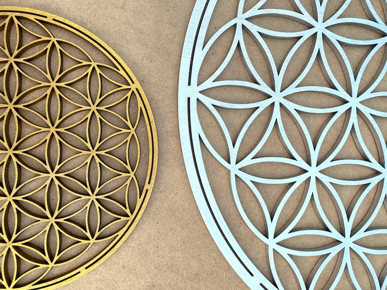 May include: Two wooden wall decor pieces in the shape of a flower of life. One is gold and the other is silver.