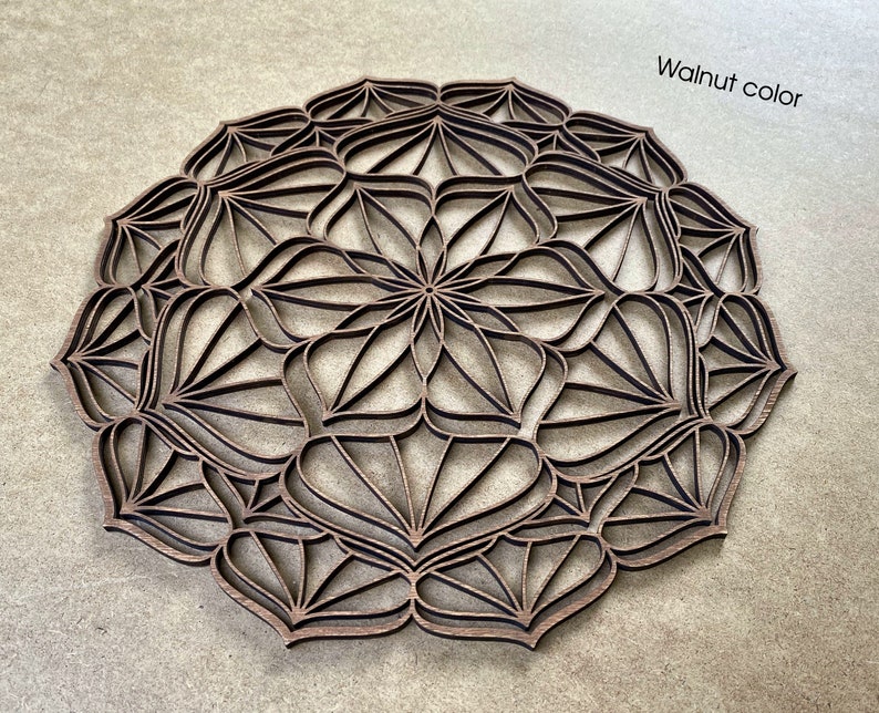 Op de afbeelding: Een walnootkleurig houten mandala met een ingewikkeld geometrisch ontwerp. De mandala is rond en heeft een centraal bloemvormig patroon.
