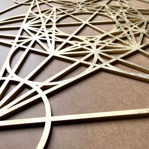 May include: A gold-colored geometric design made of wood, resembling a complex pattern of overlapping circles, triangles, and squares.
