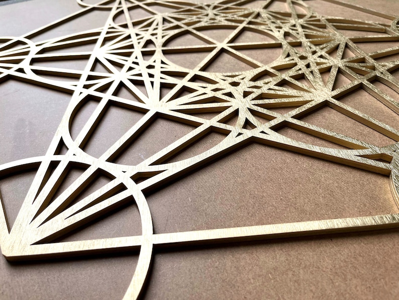 May include: A gold-colored geometric design made of wood, resembling a complex pattern of overlapping circles, triangles, and squares.