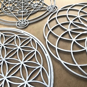 May include: Three silver metal wall decor pieces with geometric designs. The designs are intricate and detailed, and the pieces are all circular in shape.
