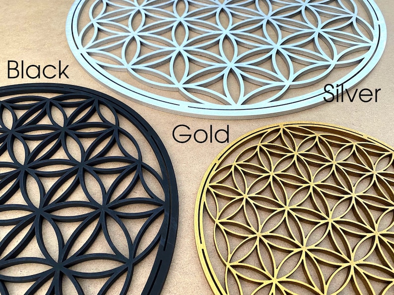 May include: Three wooden wall decor pieces in the shape of a flower of life pattern. The pieces are in black, silver, and gold.