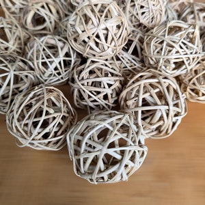 May include: A group of natural woven wicker balls in a light beige color. The balls are made of thin, interwoven strands of natural material, creating a delicate and airy appearance.