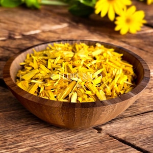 Puede incluir: Un tazón de madera lleno de pétalos de flores amarillas secas. El tazón está sobre una superficie de madera.