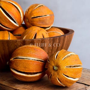 May include: A wooden bowl filled with dried orange slices. The orange slices have been cut and dried to create a decorative and fragrant element.