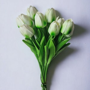 Peut inclure: Un bouquet de tulipes blanches avec des tiges et des feuilles vertes. Les tulipes sont li&eacute;es ensemble avec un ruban brun.