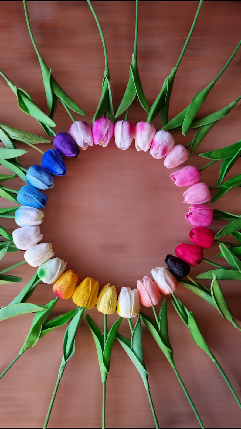 Peut inclure: Un cercle de tulipes artificielles color&eacute;es dispos&eacute;es en arc-en-ciel sur un fond brun.